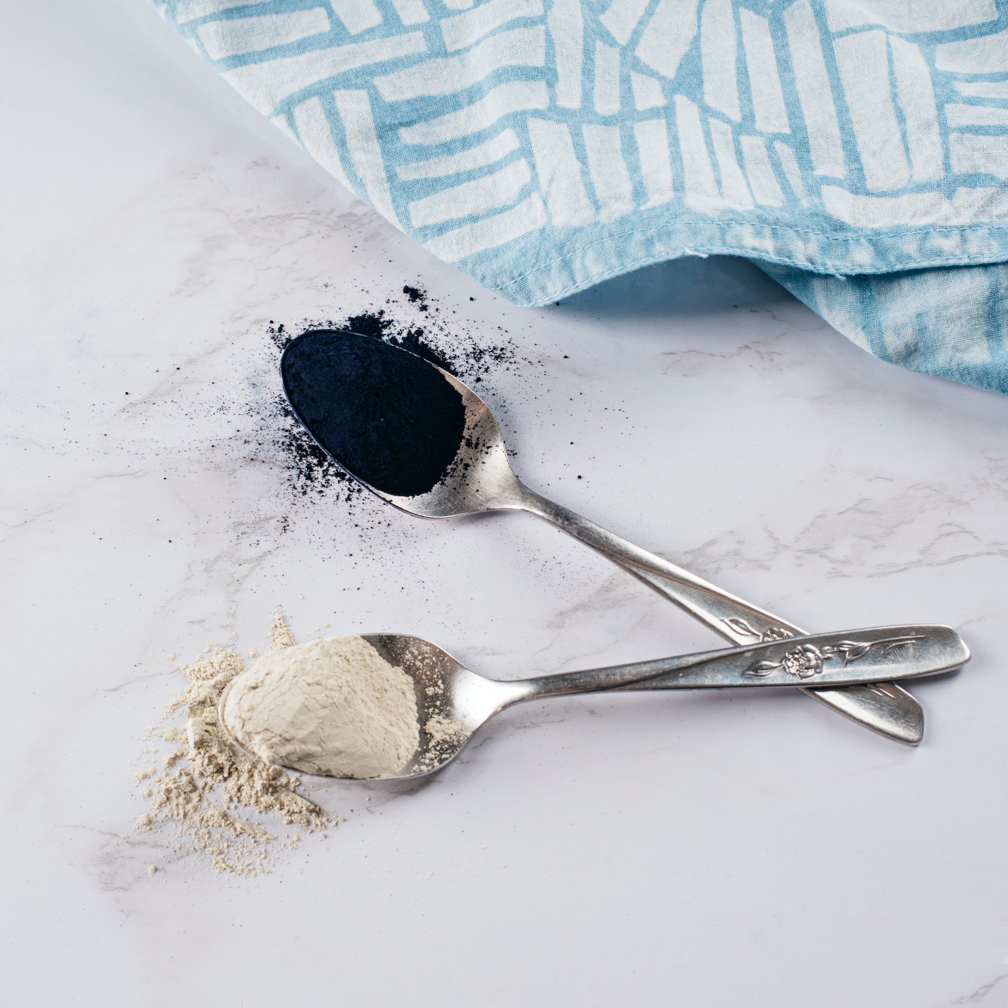 Two crossed silver teaspoons with powdered kit ingredients
