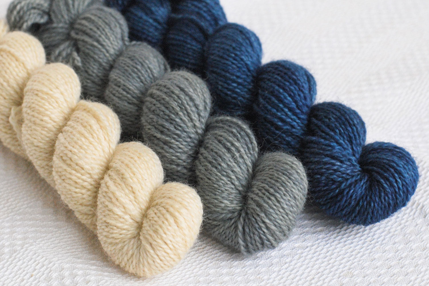 Set of three hand-dyed mini-skeins in natural, grey, and dark blue