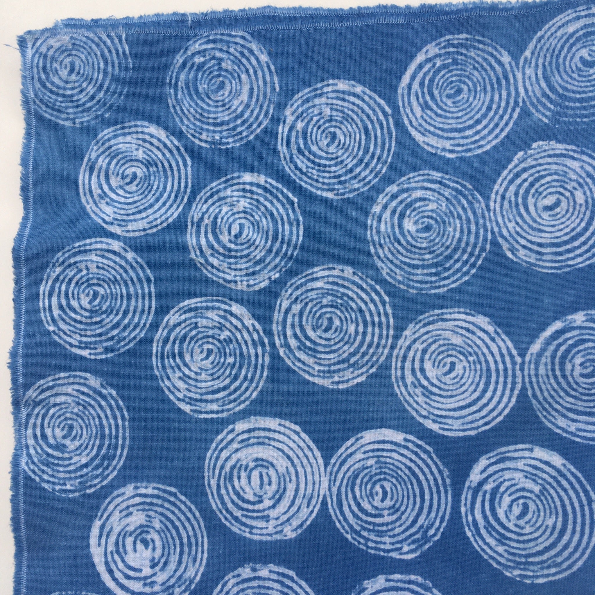 Fabric example dyed with clay resist: deep indigo blue with circular pattern in white.
